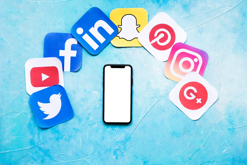 An illustration shows a black mobile phone surrounded by various social media platforms